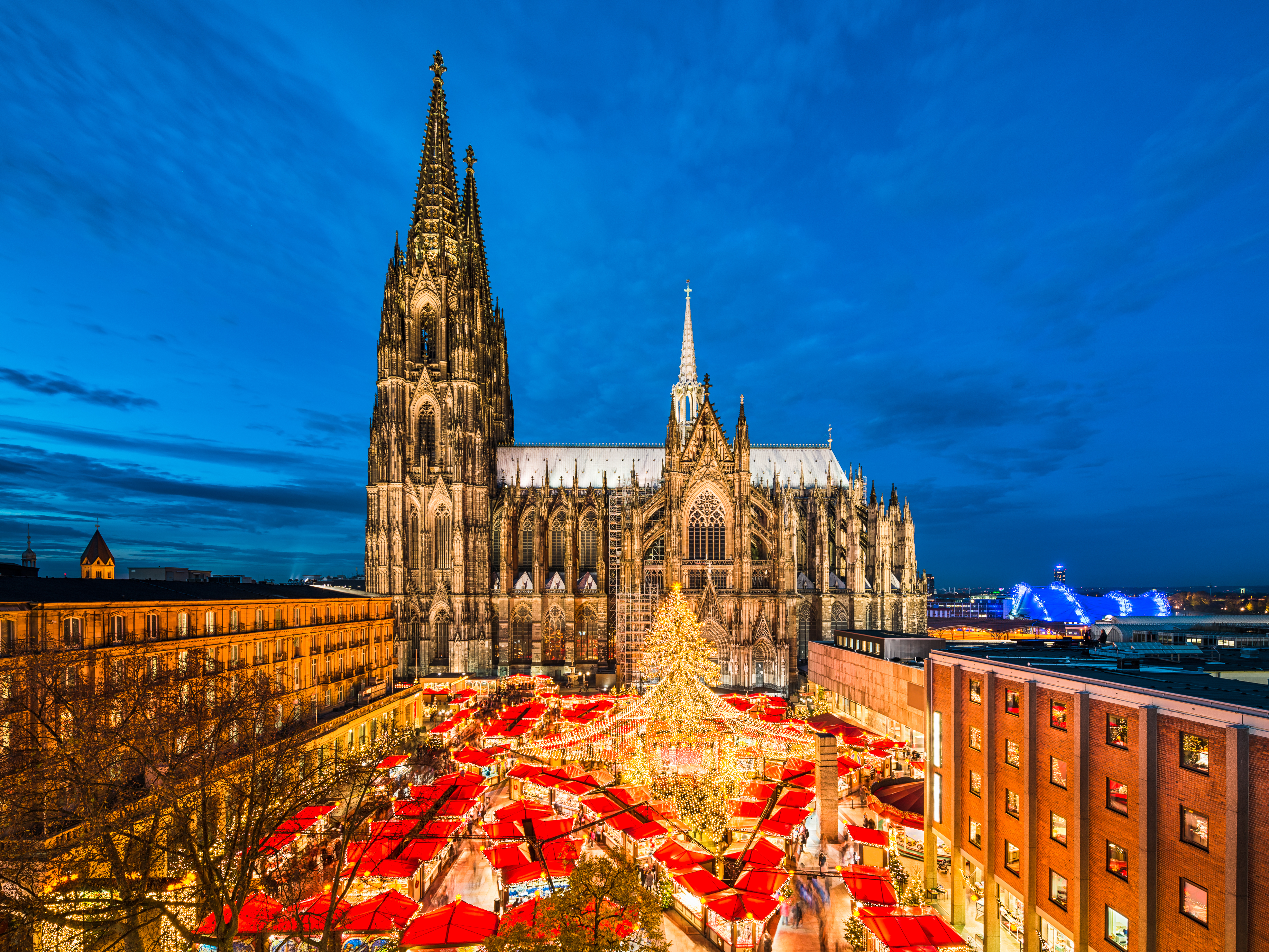 View of the Cologne Christmas market with the Cologne cathedral as a backdrop at dusk.