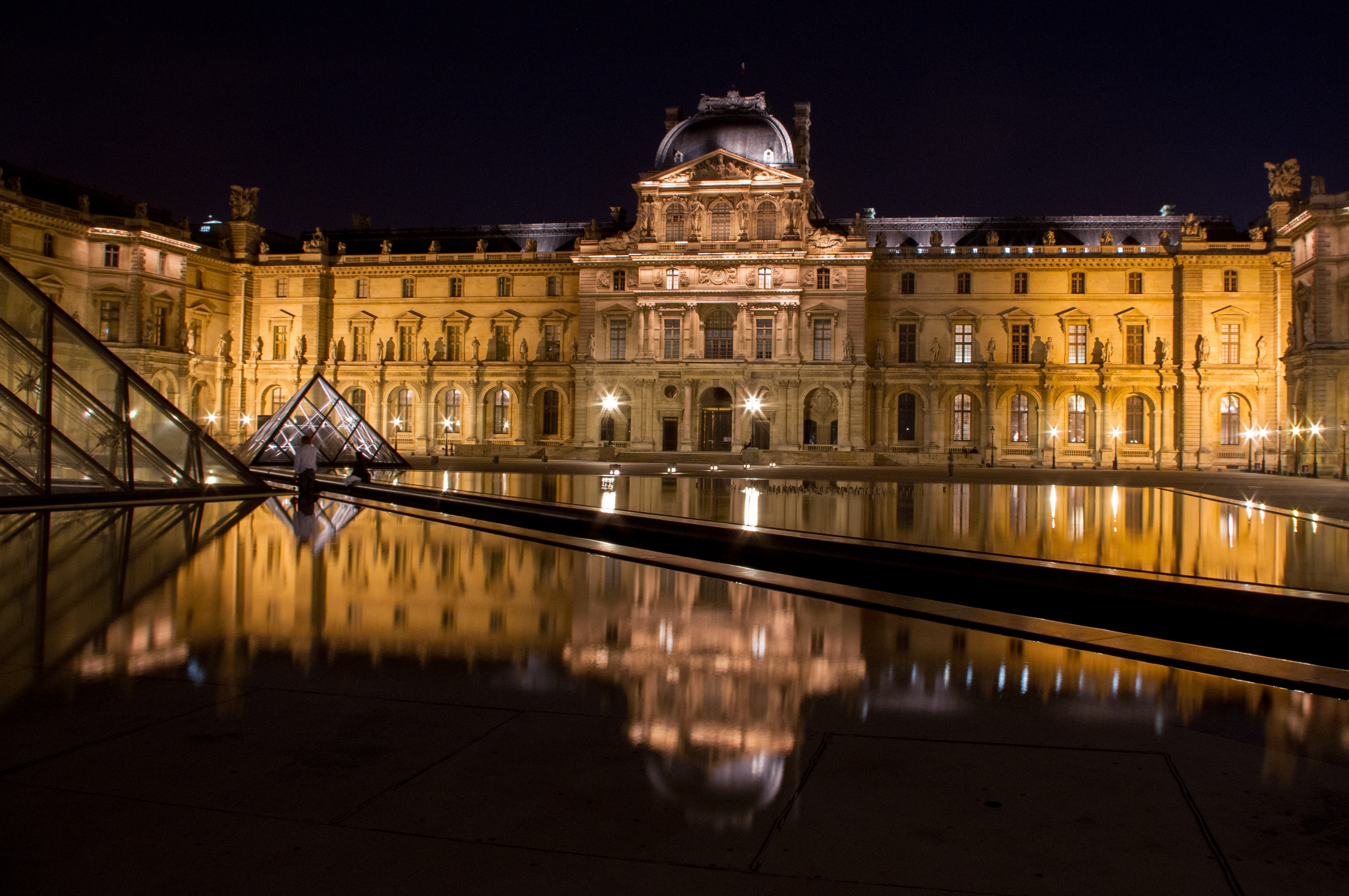 The Louvre in Paris, France shot at night with reflections from the pools