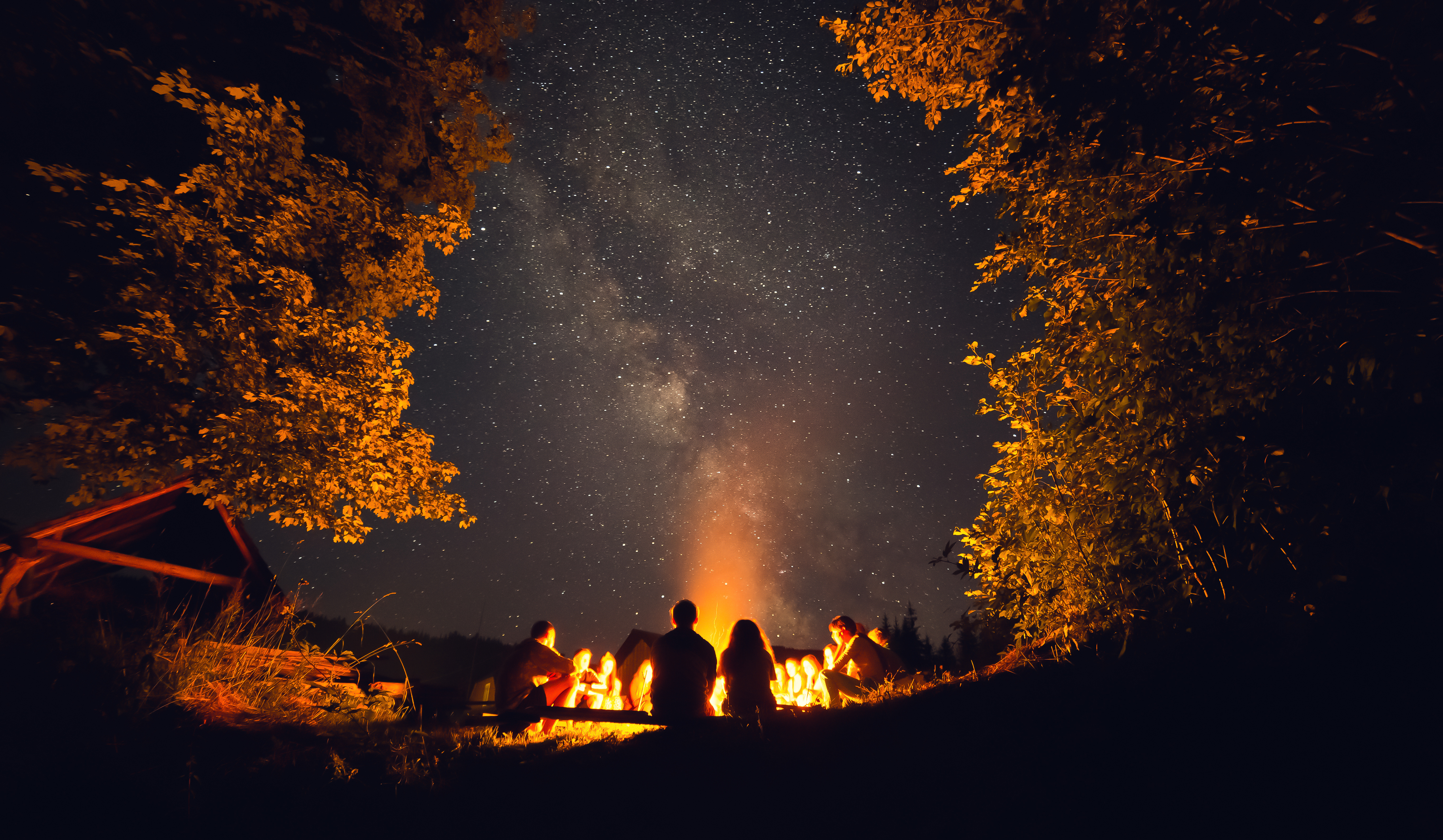 Young people sitting around a camp fire at night.